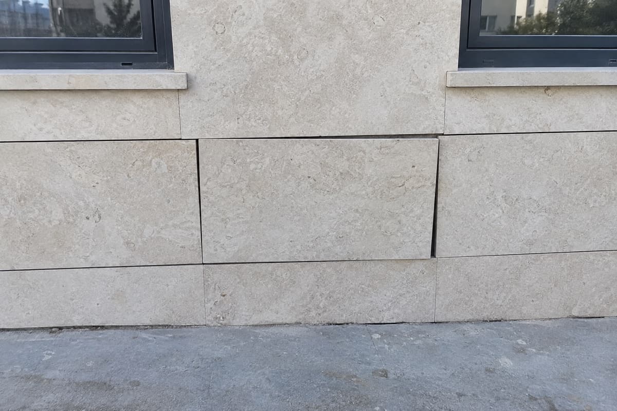 חיפוי אבן בחזית בניין, לוח אחד בולט מהקו והמישקים סביבו לא אחידים