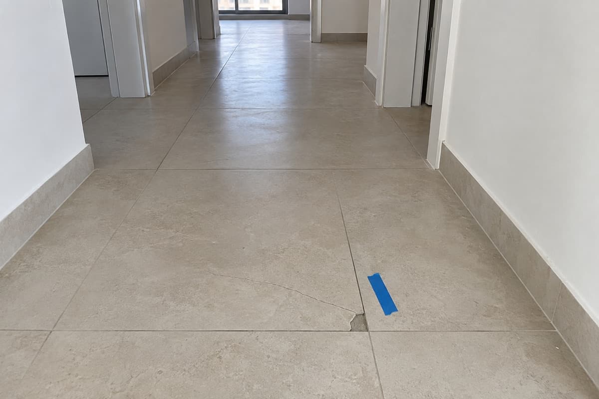 אריח רצפה סדוק בפרוזדור, מסומן בסרט כחול